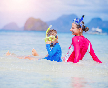 可爱的女孩和男孩在热带海滩游泳