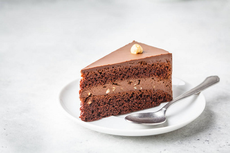 一块巧克力蛋糕放在白色盘子里，白色背景，复印空间。纯素甜点，植物为基础的食品理念..