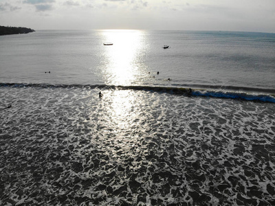 在日落时，冲浪者在船上等待海浪的鸟瞰图，大浪热带蓝色海洋，无人驾驶冲浪者捕捉蓝色海浪的鸟瞰图，印度尼西亚巴厘岛