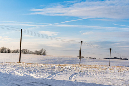 阳光明媚的冬日，空旷的乡村景观，积雪覆盖地面，框架中的电力线，抽象的背景，有趣和快乐的概念