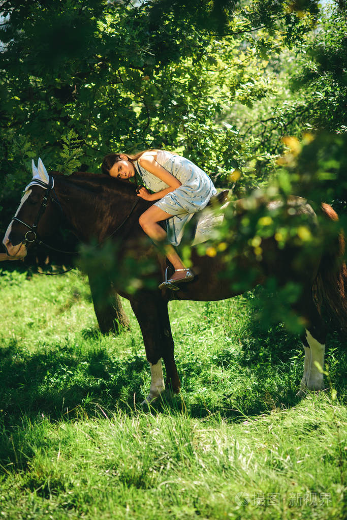 漂亮的女人骑在夏天的风景上骑马.可爱的女孩在马场.