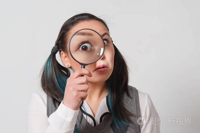 漂亮的年轻女人透过放大看灯光背景