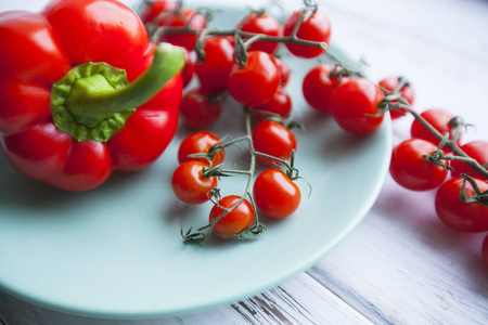 饮食健康食品素食理念。 红色甜辣椒和有机樱桃番茄在蓝色盘子白色木制背景关闭