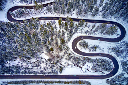 罗马尼亚特兰西瓦尼亚弯曲公路的空中景色，冬季无人机在高山通道上用雪覆盖的树木