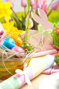 木制复活节兔子五颜六色的鸡蛋和鲜艳的花朵。 复活节概念