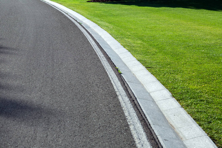 草坪路旁沥青路,道路一侧有雨水,道路沿线有一条沟渠和一片绿色草坪.