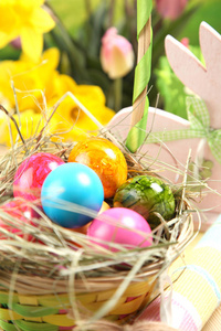 木制复活节兔子五颜六色的鸡蛋和鲜艳的花朵。 复活节概念