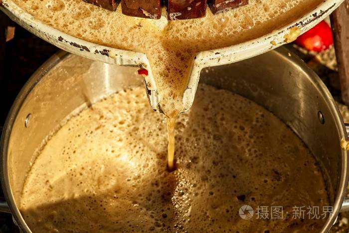 压榨新鲜苹果汁从压榨机流出的果汁