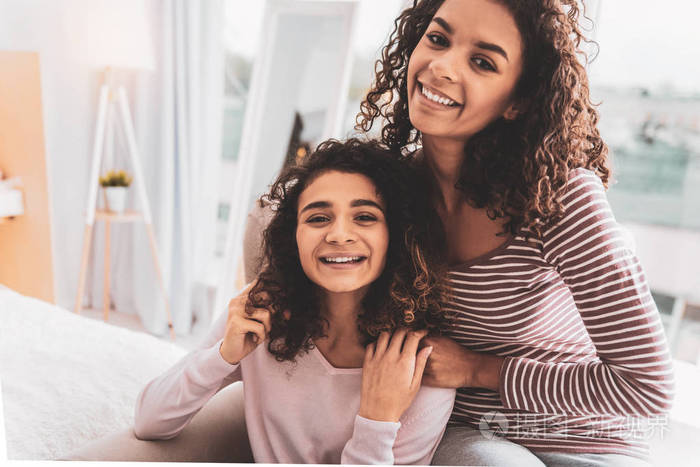 两个微笑的女孩坐在扶手椅附近装饰植物
