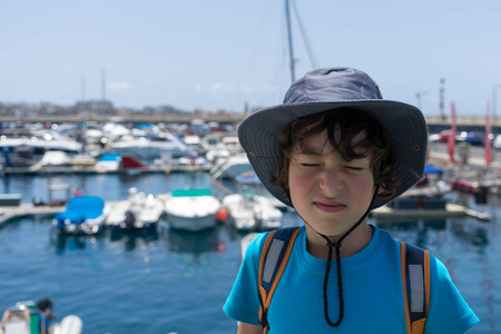 一个男孩在一艘游艇甲板上的肖像，从阳光下闭上了眼睛。