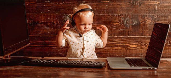 儿童男孩在耳机与麦克风在呼叫中心。使用计算机技术的呼叫中心操作员