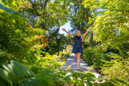 年轻漂亮的高加索女人在夏天阳光明媚的日子里散步. 户外绿树照片
