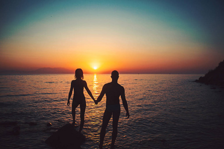 浪漫的情侣在海滩上看日落在暮色中