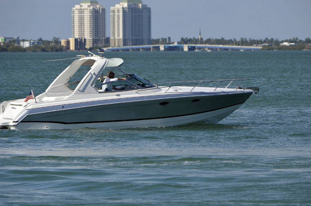 银色和白色高端摩托艇在佛罗里达州沿海水道与北米米公寓和一个吊桥的背景下巡航。