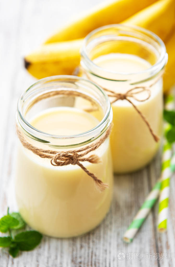 香蕉酸奶和新鲜香蕉在木制背景上