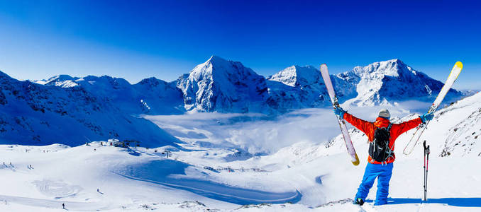 登山者沿着雪山脊滑雪，手臂张开。 在背景蓝天和闪亮的太阳和奥特勒在南蒂罗尔意大利。 冒险冬季极限运动。