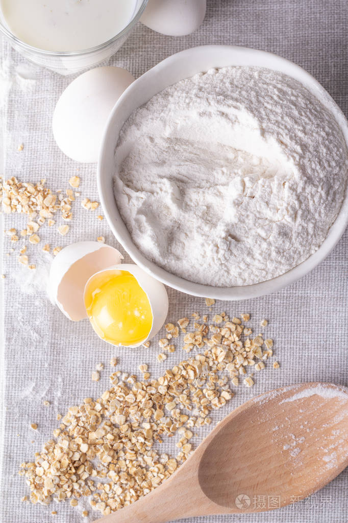 面粉鸡蛋和燕麦牛奶的顶部视图灰色背景