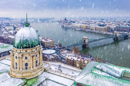 布达佩斯匈牙利空中俯瞰白雪皑皑的布达城堡皇家宫殿的穹顶，上面有szecheny i链桥和匈牙利议会在冬天的时候。