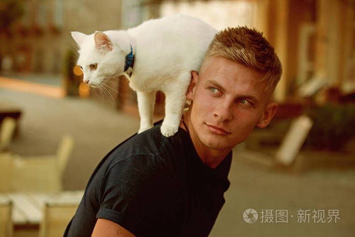 肌肉发达的男人抱着可爱的血统猫.快乐的猫主人与肌肉发达的外观.
