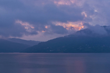 粉红色和蓝色的海景，背景是山和云