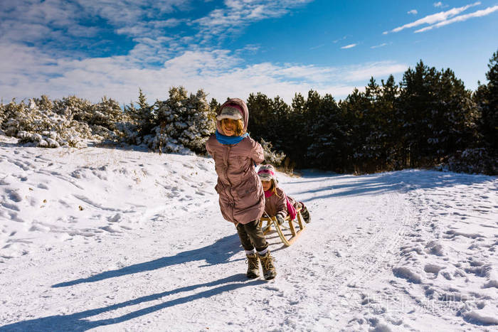 两个姐妹一起在冬山边滑雪