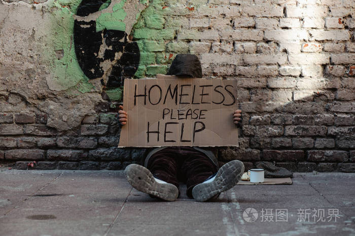 无家可归的人坐在人行道上要求施舍