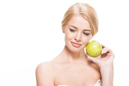 美丽的忧郁的金发女孩，手里拿着绿色的苹果，俯视着孤立的白色