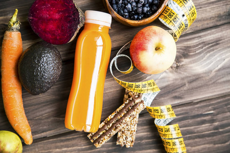 健康的生活方式概念，有果汁瓶，蔬菜和水果，有麦片，莫斯利棒和测量带在木板上，顶部视图，健康的生活健身概念