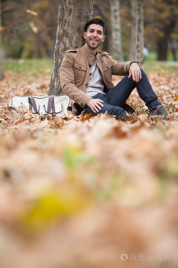 年轻的成年男子英俊的摆姿势在树林里,冬天,秋天,白天