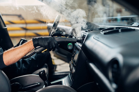 洗车服务男工人手套，用蒸汽清洁剂清除灰尘和污垢。 专业干洗汽车内饰