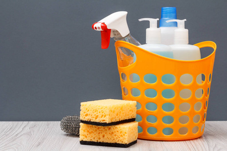 塑料篮子，带有保护性手套，瓶子，洗碗液，玻璃和瓷砖清洁剂，用于微波炉和在灰色背景。 洗涤和清洁的概念。