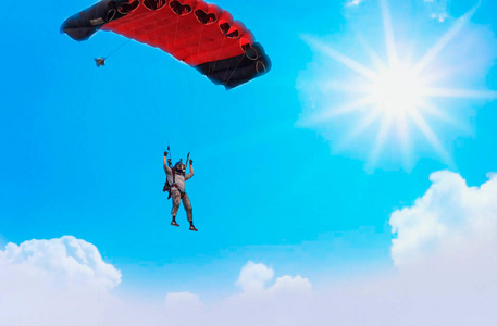 带着红色降落伞降落在蓝天上的降落伞照片
