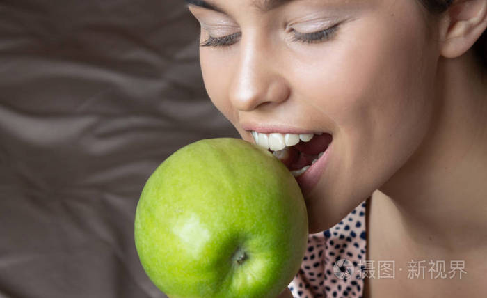 美丽的女人咬绿苹果完美的牙齿牙科