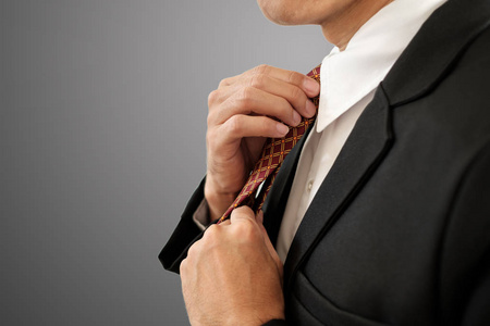 商人用剪裁路径把领带系在灰色背景上。