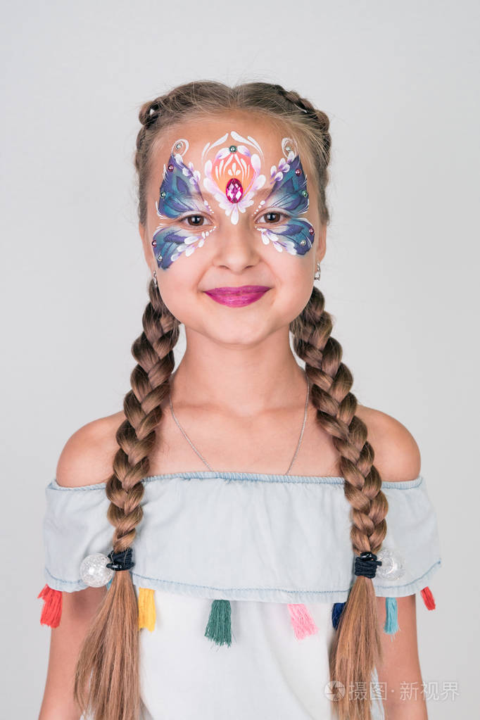 迷人的女孩与蓝色蝴蝶画在她的脸上在白色的背景面部彩绘