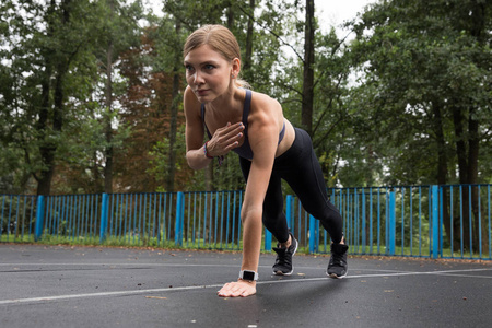 健身模型在运动顶部和腿部做运动锻炼在运动场在公园。 完美的女性身材