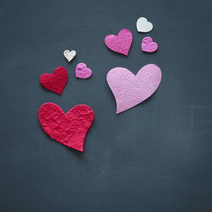 s day concept. pink and red paper hearts over blackboard