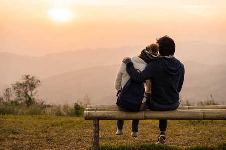 有爱的一对夫妇在日落时拥抱在山上，面对美丽的风景。