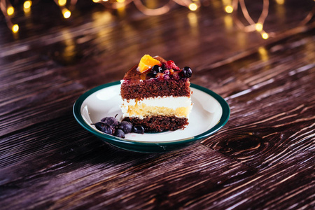 一块蛋糕，加奶油巧克力水果甜点，木制背景，有bokeh灯