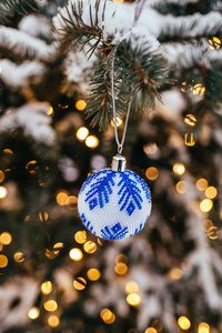 蓝白色圣诞球在杉树枝上，关闭金黄色的灯光背景