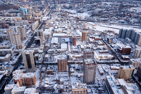 冬季景观从鸟瞰新西伯利亚市，街道上有一条路，高楼大厦，屋顶白雪覆盖的房子，停车场，汽车，树木。