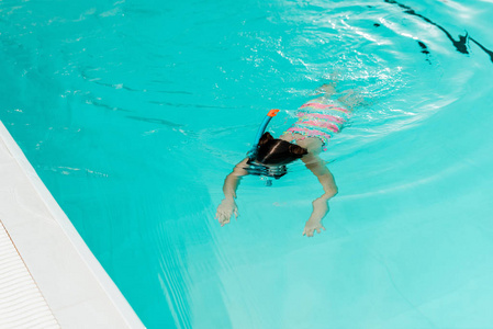 儿童在游泳池的蓝水中浮潜