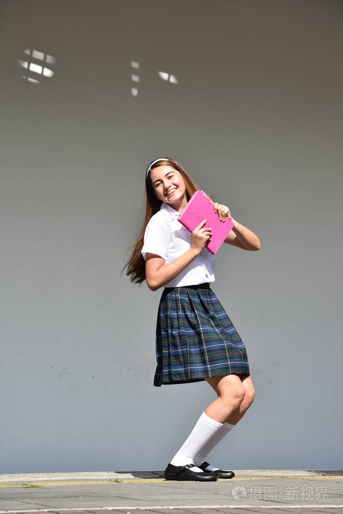 校园女孩和快乐穿着带书的裙子站着