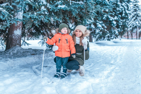 一位年轻的母亲教她的小儿子35岁的孩子滑雪。冬天在森林里有很多雪。快乐的朋友周末离开