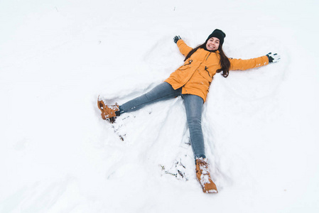 年轻的成人微笑的女人做雪天使