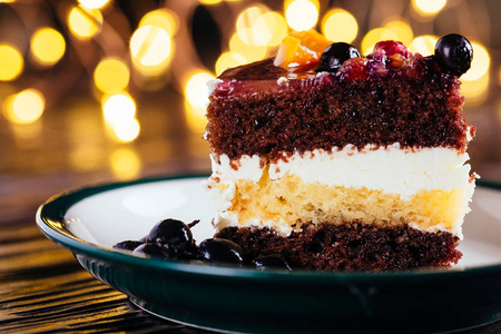 一块蛋糕，加奶油巧克力水果甜点，木制背景，有bokeh灯