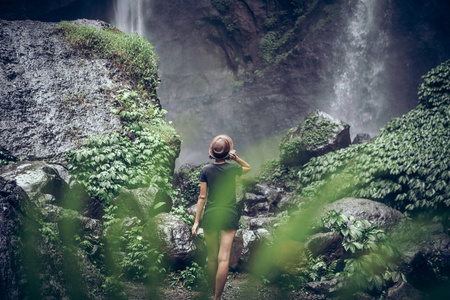 在印度尼西亚巴厘岛的热带雨林中, 年轻女子在一个伟大的塞库姆普尔瀑布上摆姿势