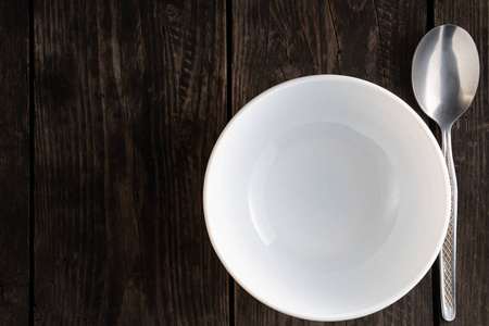 桌子上摆着空的白色盘子，用勺子放在木桌上