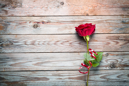 木制乡村背景上的红色玫瑰和丝带。