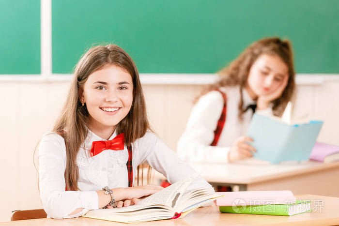 两个女学生坐在教室里的桌子上上课.